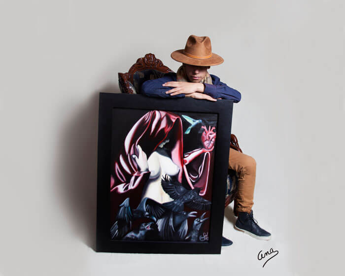 Fotografía profesional de joven con su pintura enmarcada en madera